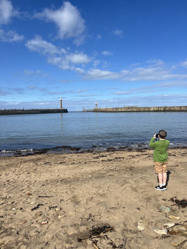 Boy taking photos on Tate Hill beach in Whitby.