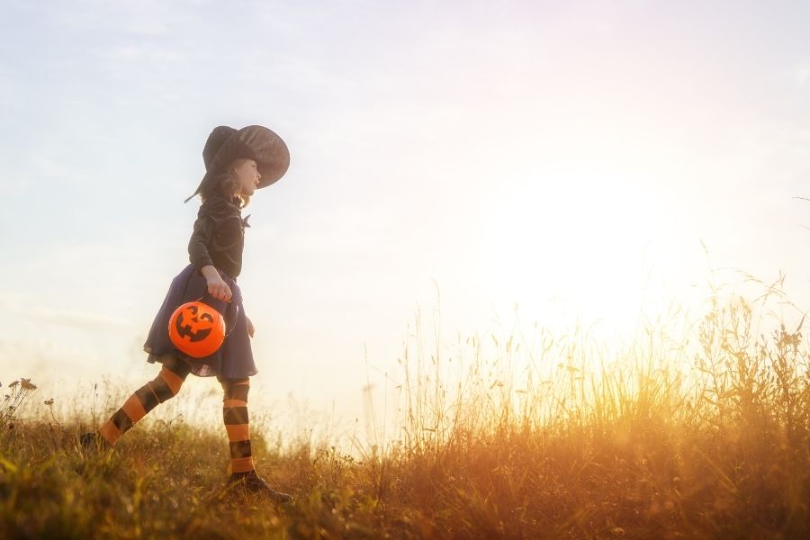 Child in the grass in halloween costume.